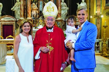 Después de recibir el primer sacramento, Alfonso –que tiene un año y medio– posa en brazos de su padre, junto a su mamá y el sacerdote.