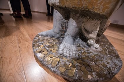 Detalle de los pies de una escultura que tiene incrustadas las monedas que los padres almaceneros del artista guardaban en un frasco