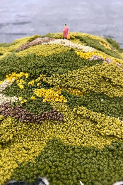 Detalle de obra, con una figura sumida en la naturaleza bordada.