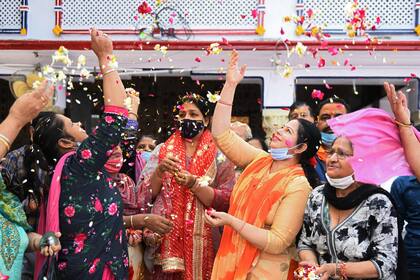 Devotas hindúes lanzan pétalos de flores mientras celebran Holi, el festival de colores de primavera, en un templo en Amritsar