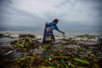 Un joven junta basura del mar en Manila, Filipinas