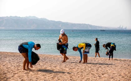Los surfistas participan en el día internacional de limpieza de playas frente a la ciudad turística de Eila, en el sur del Mar Rojo de Israel