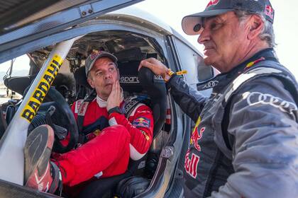 Diálogo de dos gigantes del automovilismo al finalizar la tercera etapa del Dakar: el francés Sébastien Loeb, nueve veces campeón mundial de rally, escucha al español Carlos Sainz, ganador en tres ocasiones del Touareg y monarca del WRC en 1990 y 1992.