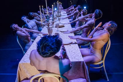 Dieciocho comensales perfectamente sincronizados abren la obra con un cuadro sabroso y grotesco