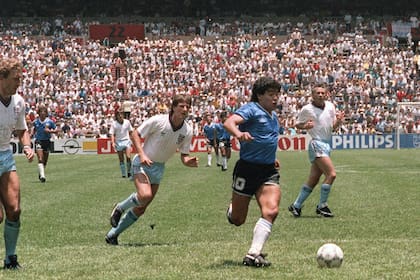 Diego Armando Maradona, seguido por Terry Butcher y Terry Fenwick, se encamina a convertir el segundo gol contra Inglaterra. La camiseta que usó esa tarde será subastada próximamente