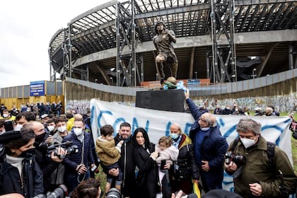 Diego Jr. y su familia rodean la estatua de Maradona inaugurada en el primer aniversario de su muerte, frente al estadio que lleva su nombre, en Nápoles, Italia