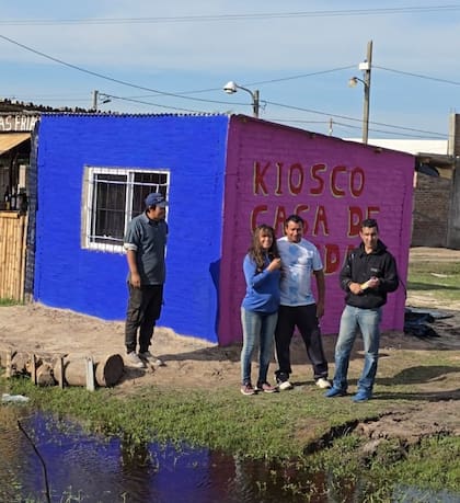 Diego junto a los dueños de un kiosco que pintó.