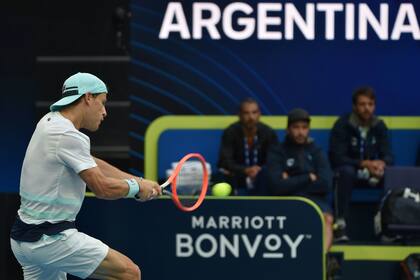 Diego Schwartzman en acción; sus compañeros observan el partido detrás; el particular formato de la ATP Cup