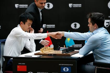 Ding Liren de China, izquierda, e Ian Nepomniachtchi de Rusia se dan la mano antes de definir el Campeonato Mundial de Ajedrez de la FIDE en Astana, Kazajstán