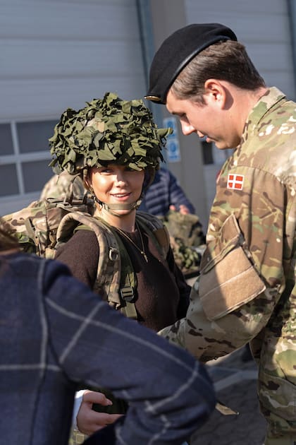 Divertida, la princesa Isabella se prueba el casco y la mochila de combate de su hermano.