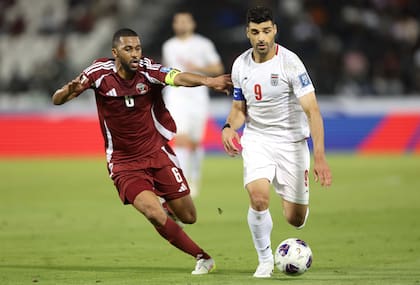 Mehdi Taremi conduce el balón presionado por Abdulaziz Hatem, de Qatar, durante la eliminatoria asiática para la Copa del Mundo de 2026.
