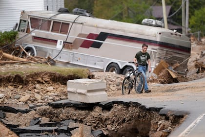 Dominick Gucciardo camina hacia su casa tras el paso del huracán Helene, el jueves 3 de octubre de 2024, en Pensacola, Carolina del Norte. (AP Foto/Mike Stewart)