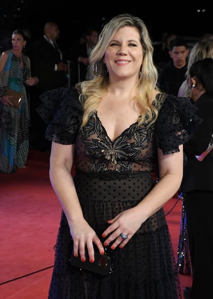 Dominique Metzger, con un diseño de Javier Saiach en tul color azul marino y motas en terciopelo negro, con unos importantes volados con crin y una pechera bordada en hilos de seda y flores en nude, negro y color vainilla, falda con movimiento y muchas capas de tul. Acompañó con joyas de Jean Pierre: un par de aros de volumen, acompañados por una argolla doble de titanio negro con brillantes y anillo de zafiros con rodio negro