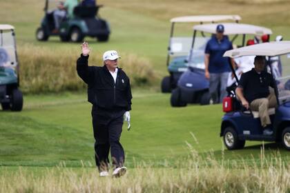 Donald Trump saluda a los manifestantes mientras juega al golf en Turnberry, Escocia, en julio del año pasado