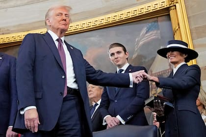 Donald Trump toma la mano de su esposa, Melania Trump, junto a su hijo Barron, al prestar juramento durante las ceremonias de inauguración en la Rotonda del Capitolio, el 20 de enero de 2025.