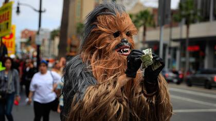 Donte, un músico que sólo dio su nombre, endereza billetes de dólar en su primer día en un nuevo traje Chewbacca comprado en eBay por $ 441, en la sección Hollywood de Los Ángeles