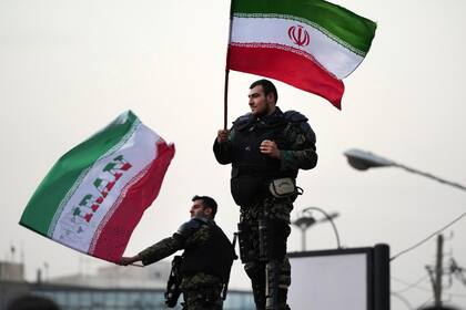 Dos agentes antimotines ondean banderas iraníes en las calles de Teherán durante la celebración de la victoria de Irán ante Gales en el Mundial de Qatar.