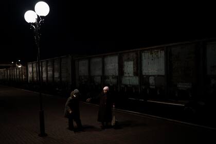 Dos ancianas ucranianas caminan hacia el tren de Jersón a Kiev en la estación de Jersón, en el sur de Ucrania, el lunes 21 de noviembre de 2022. (AP Foto/Bernat Armangue)