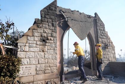 Dos bomberos examinan los daños en la iglesia episcopal San Marcos después de que fue destruida por el incendio Eaton, el viernes 10 de enero de 2025, en Altadena, California. (AP Foto/Chris Pizzello)