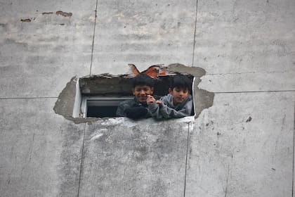 Dos chicos se asomaban por una ventana del edificio de Santa Cruz 140, mientras las familias permanecían encerradas en el edificio hasta que se definiera la situación