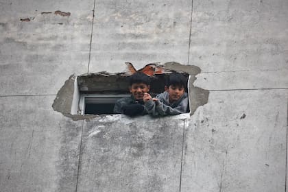 Dos chicos se asomaban por una ventana del edificio de Santa Cruz 140, mientras las familias permanecían encerradas en el edificio hasta que se definiera la situación 