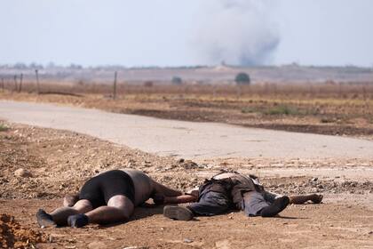 Dos cuerpos yacen en el suelo cerca de una carretera en Kfar Aza, al sur de Israel, fronterizo con la Franja de Gaza, el 10 de octubre de 2023.