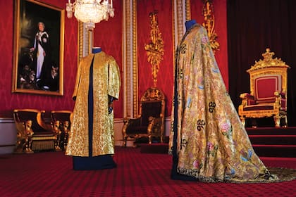 Dos de las vestiduras claves de la coronación de Carlos III: el manto imperial (a la derecha) y la supertúnica (izquierda). Realizada por Wilkinson & Son para la coronación del rey Jorge V, en 1911, la supertúnica tiene la forma de un abrigo dorado de manga larga. 