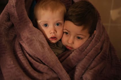 Dos hijos de  trabajadores médicos de la maternidad de Mariupol, envueltos en frazadas por el intenso frío de la noche