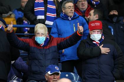 Dos hinchas de fútbol usan máscaras del primer ministro del Reino Unido, Boris Johnson, y el presidente de Estados Unidos, Donald Trump, con barbijos en un partido en Escocia