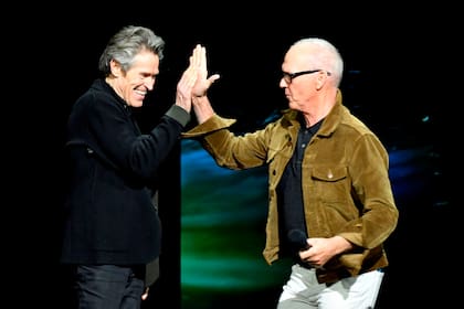 Dos icónicos actores de Hollywood, Michael Keaton y Willem Dafoe, chocan las manos durante la presentación de Warner Bros Pictures