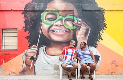 Dos lugareños frente a uno de los grafittis de Jota Villarreal, artista visual que lidera una movida para dotar de graffitis.