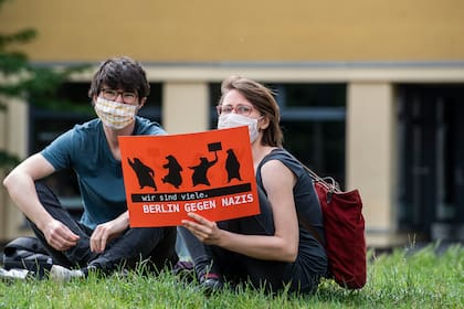 Dos manifestantes con máscara facial sostienen un cartel que dice: "Somos muchos, Berlín contra los nazis" durante una protesta de grupos de izquierda en Berlín por el confinamiento el 23 de mayo de 2020