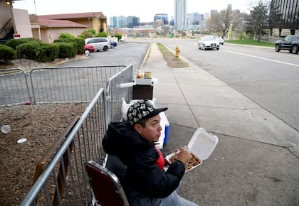 Dos migrantes latinos comen en la puerta de un motel en EE.UU. (Archivo AP Foto/Thomas Peipert)