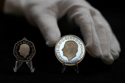 Dos monedas nuevas muestran el retrato oficial del rey Carlos III: una de 50 peniques a la izquierda y una de 5 libras a la derecha, en Londres, el jueves 29 de septiembre de 2022. (AP Foto/Alastair Grant)