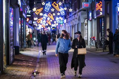 Dos mujeres caminan debajo de los decorados con luces navideñas en una calle del centro de Amsterdam