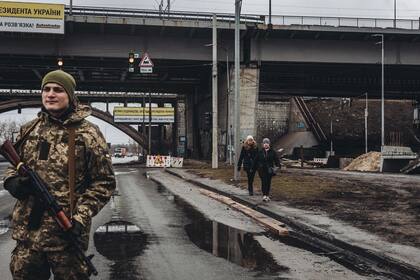  Dos mujeres caminan frente a un miliciano ucraniano, a 2 de marzo de 2022, en Kiev (Ucrania)