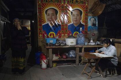 Dos mujeres pasan la tarde en su casa, decorada con carteles de Mao Zedong en Manhaguo, en Yunnan, en el sur de China, el miércoles 2 de diciembre de 2020