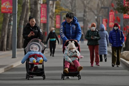 Dos mujeres pasean con niños por un parque en Pekín, China, el 19 de enero de 2023. 