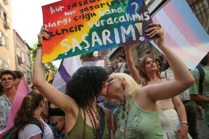 Dos mujeres se besan mientras sostienen una pancarta en turco, que dice "vivo libre. ¿Quién es el tonto que me encadena? Me sorprendería" durante una marcha del Orgullo LGTBQ en Estambul, Turquía, el domingo 26 de junio de 2022. (AP Foto/Emrah Gurel)