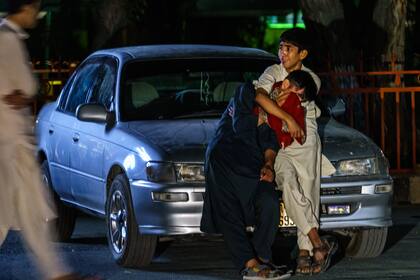 Dos niños se abrazan mientras lloran en el estacionamiento del hospital Wazir Akbar Khan, en Kabul, Afganistán