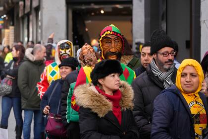 Dos personas con máscaras hacen fila para comprar lotería de Navidad en el centro de Madrid, España, el miércoles 21 de diciembre de 2022. El sorteo de Navidad da inicio a las celebraciones navideñas tradicionales en España. (AP Foto/Paul White)