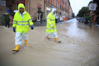 Dos personas cruzan una calle anegada en Bologna, Italia, el 16 de mayo de 2023. (Michele Nucci/LaPresse via AP)