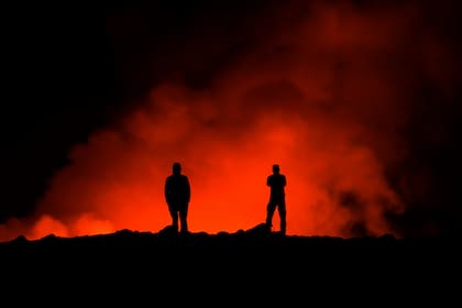Dos personas observan la erupción del un volcán, al norte de Grindavík, Islandia, el 8 de febrero de 2024. (AP Foto/Marco Di Marco)