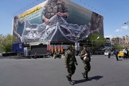 Dos policías caminan frente a una valla publicitaria antiestadounidense, el 5 de abril de 2026, en Teherán, Irán