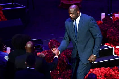 Dos potencias se saludan: Michael Jordan (sentado) y Shaquille ONeal chocan sus manos derechas; el motivo que los reúne no da como para sonrisas.