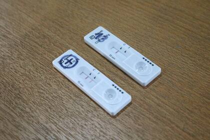 Dos test de antígenos. Uno, con una sola línea, es negativo; el otro, con dos líneas, es positivo.