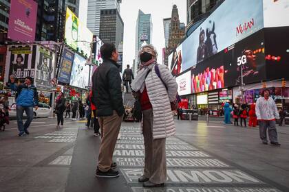 Dos turistas en Times Square utilizan barbijos