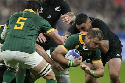 Duane Vermeulen avanza ante la marca de dos All Blacks durante la final del Mundial de Rugby que se disputa en París