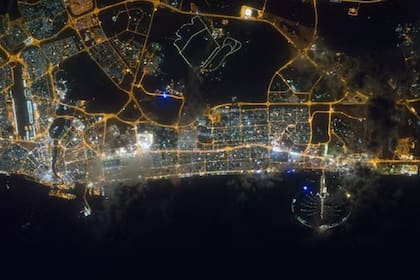 Dubái de noche, desde la ISS: las carreteras y calles principales están claramente definidas por luces de color amarillo anaranjado, mientras que las áreas comerciales y residenciales exhiben un patrón más bien blanco y azul