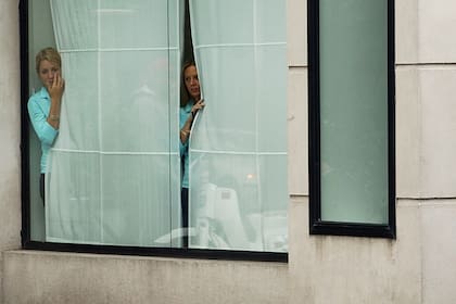 Vecinos espían por la ventana mientras se realiza el operativo policial